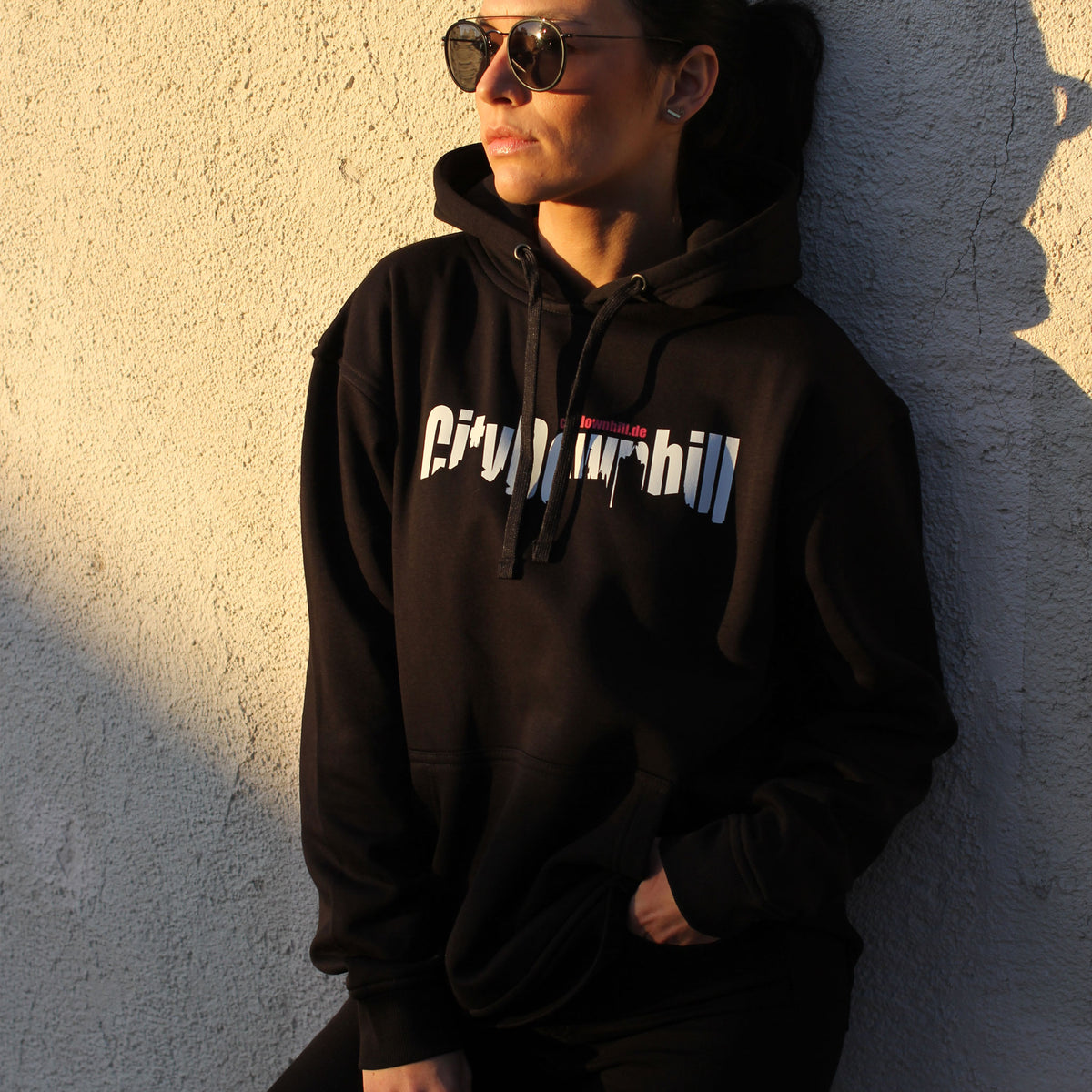 City Downhill Hoodie schwarz – Vorderansicht an einer Hauswand