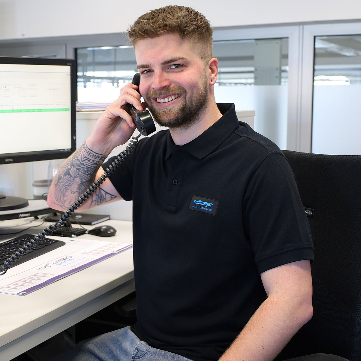 Mitarbeiter im schwarzen SEDLMAYER-Poloshirt telefoniert im Büro
