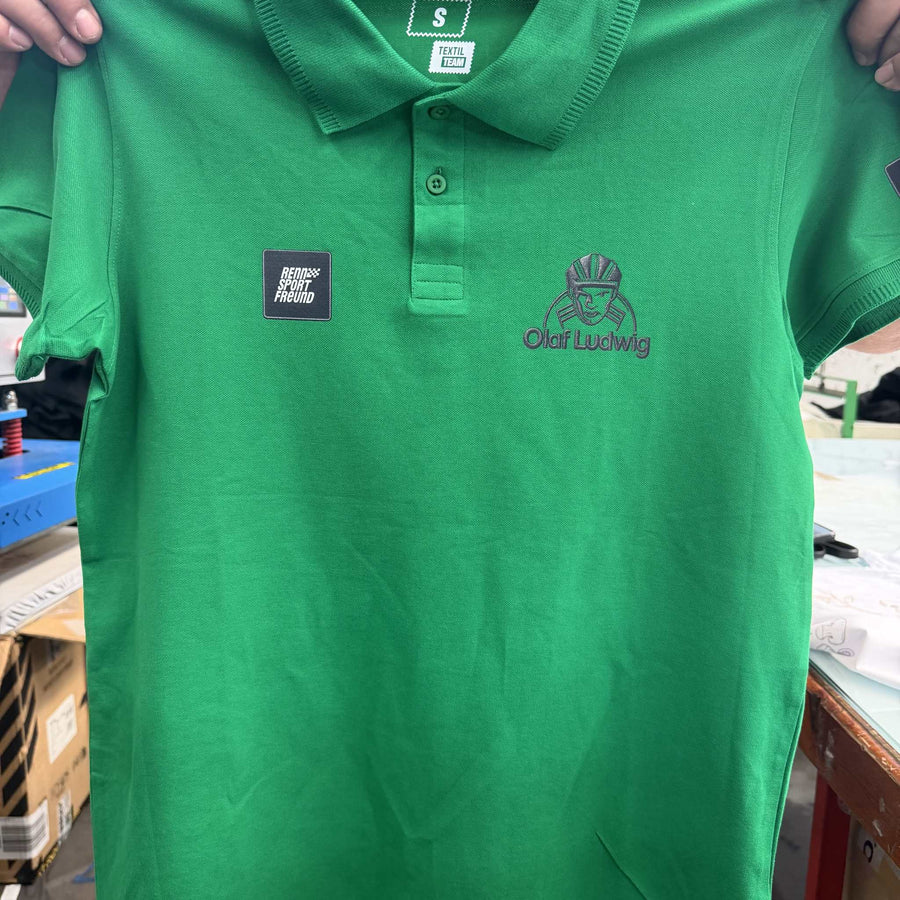 grünes Poloshirt mit einer DTF to Embroidery Technik mit den Motiven der Marke RENNSPORTFREUND und der Radfahrlegende Olaf Ludwig
